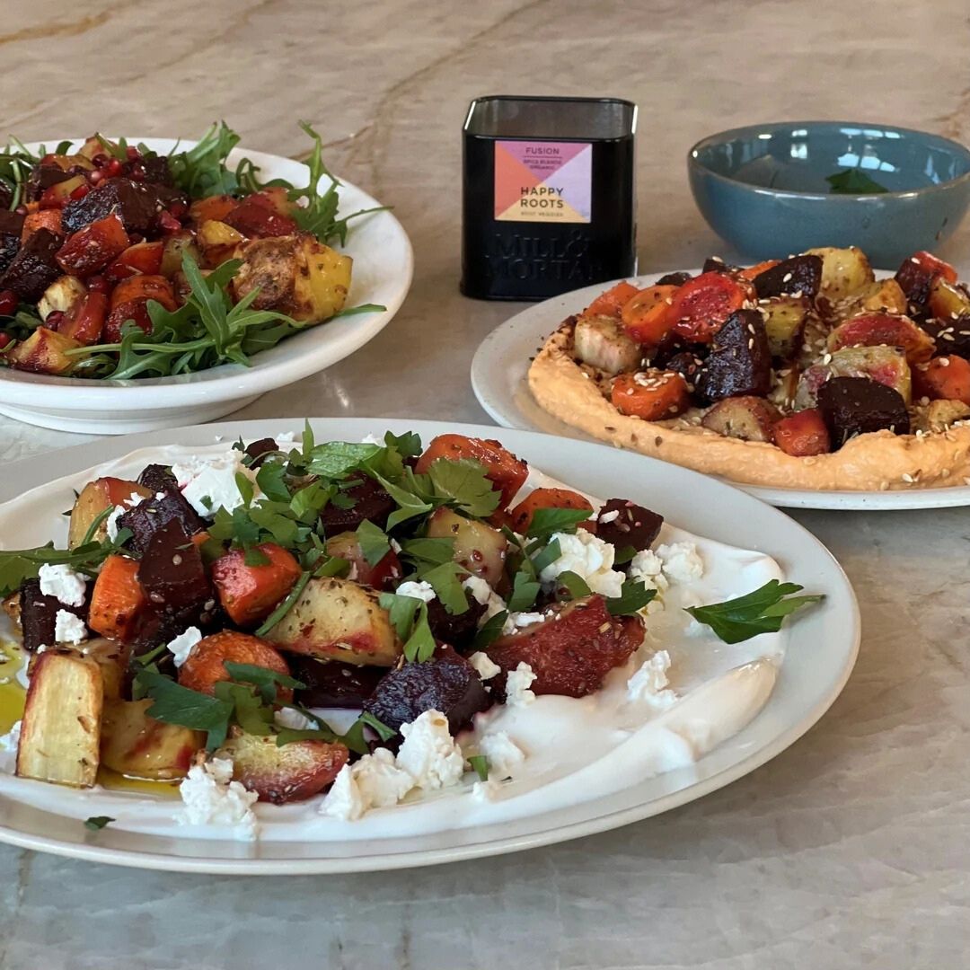 Drie borden met geroosterde wortelgroenten op verschillende manieren geserveerd: met feta en peterselie op yoghurt, met hummus en sesam, en met rucola en granaatappel.