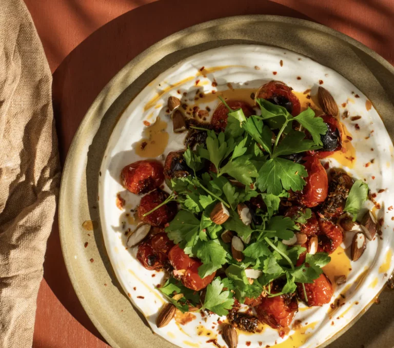 Geroosterde cherrytomaatjes met Griekse yoghurt, rozenharissa en geroosterde amandelen.