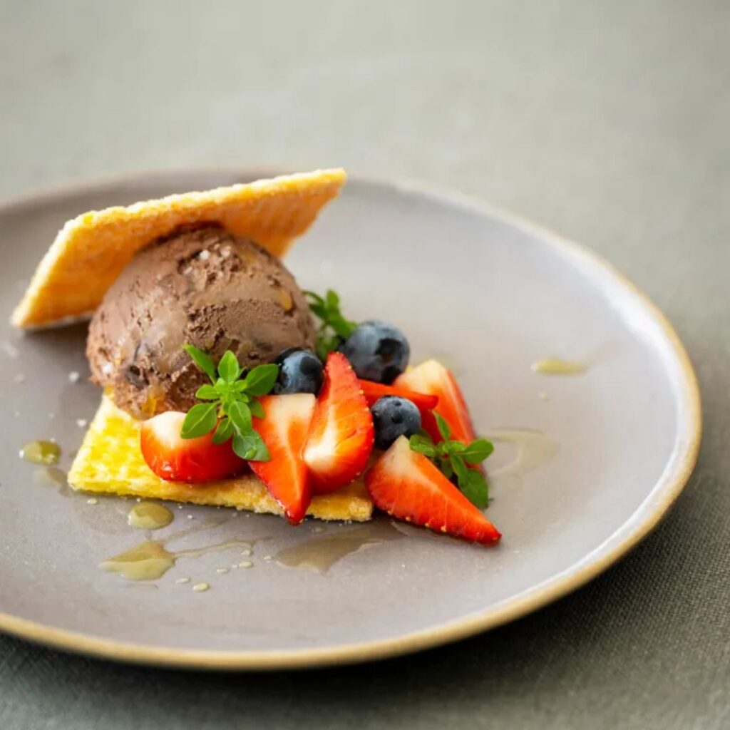 Chocolade-ijs tussen bladerdeegwafeltjes met aardbeien, blauwe bessen en munt op een grijs bord
