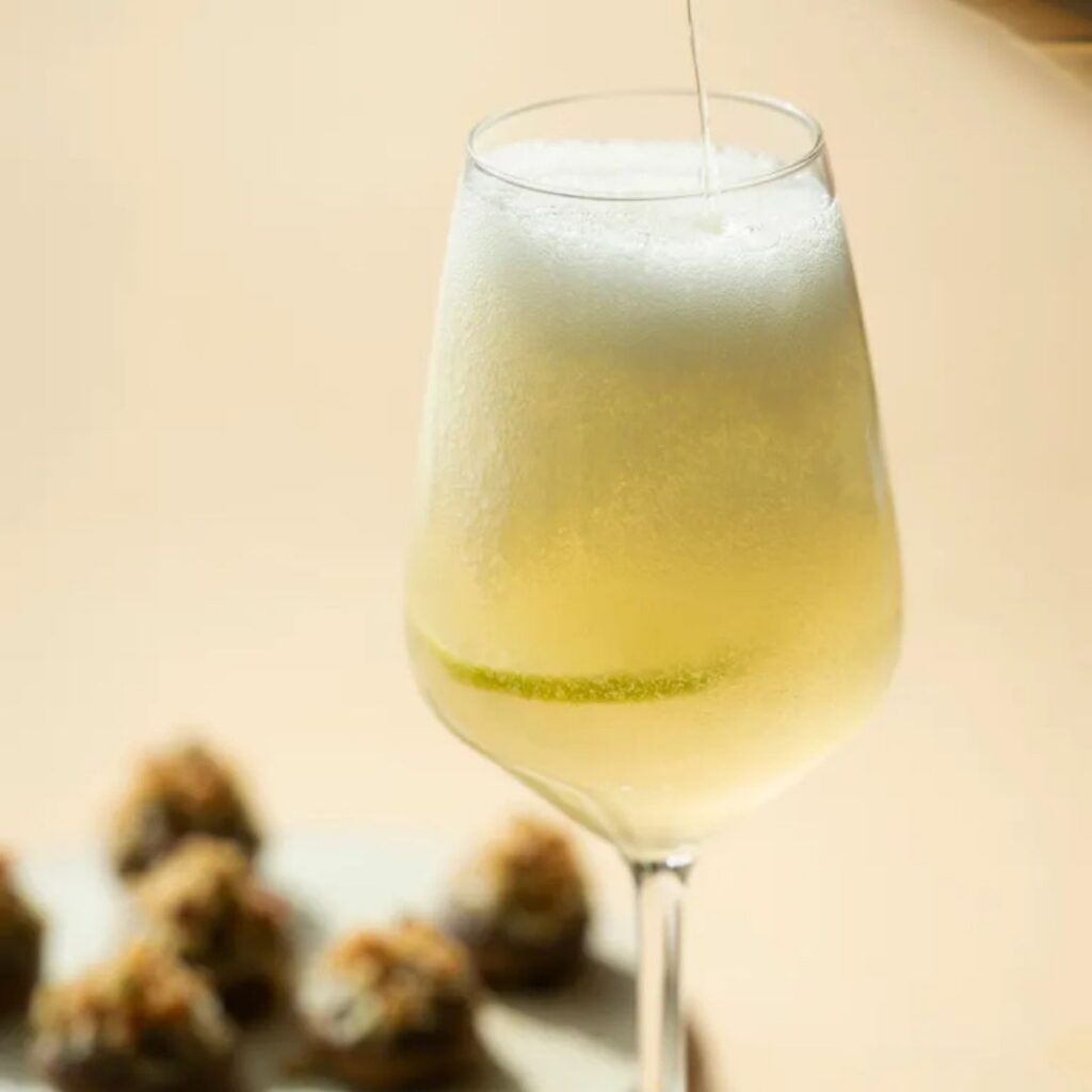 Glas truffel sprits met schuimlaagje en gevulde champignons op de achtergrond