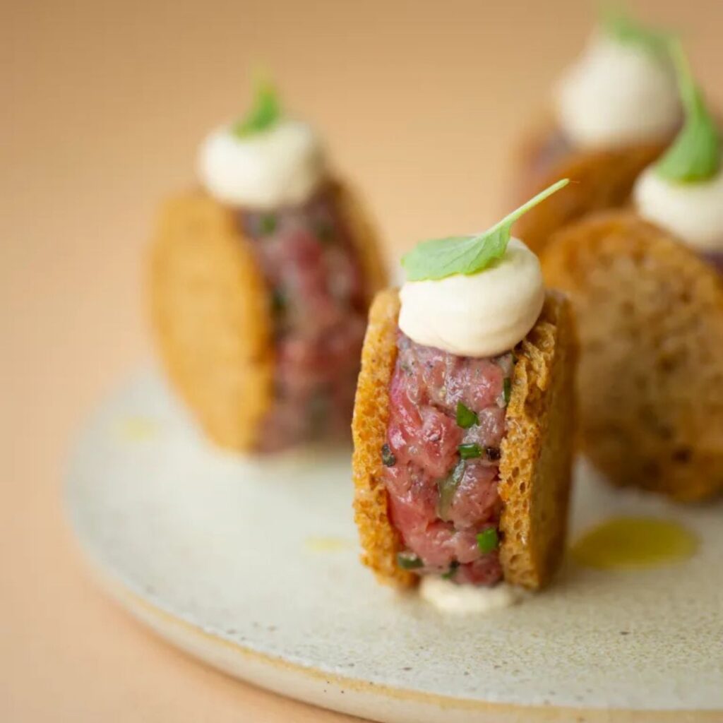 Mini-sandwich van zuurdesemtoastjes met rundstartaar, truffelkaascrème en een blaadje kruid